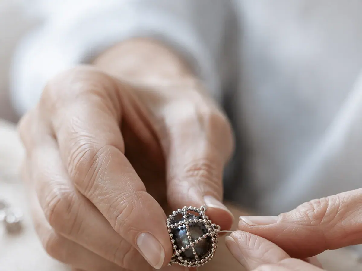 Mains qui ajustent le pendentif du Collier des montagnes